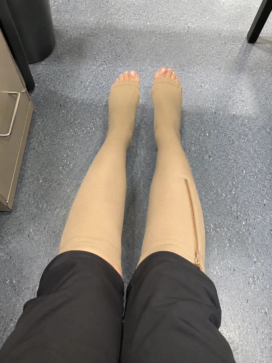 Open-toe beige compression socks worn while seated
