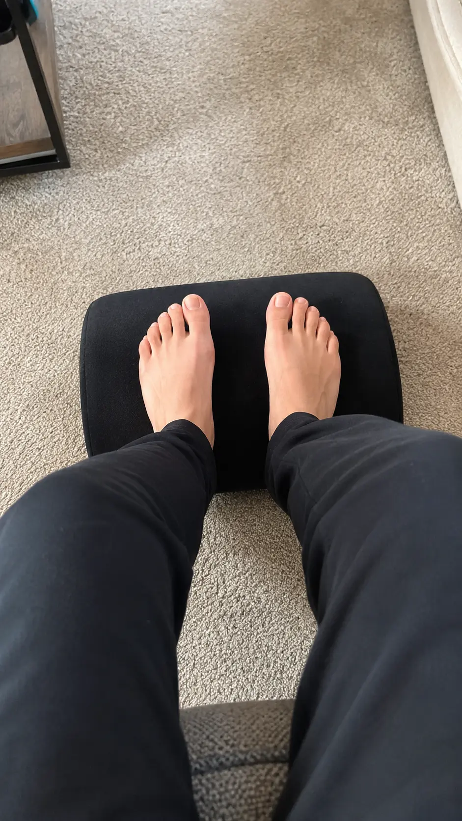 Bare feet resting flat on the Curved Comfort Footrest cushion