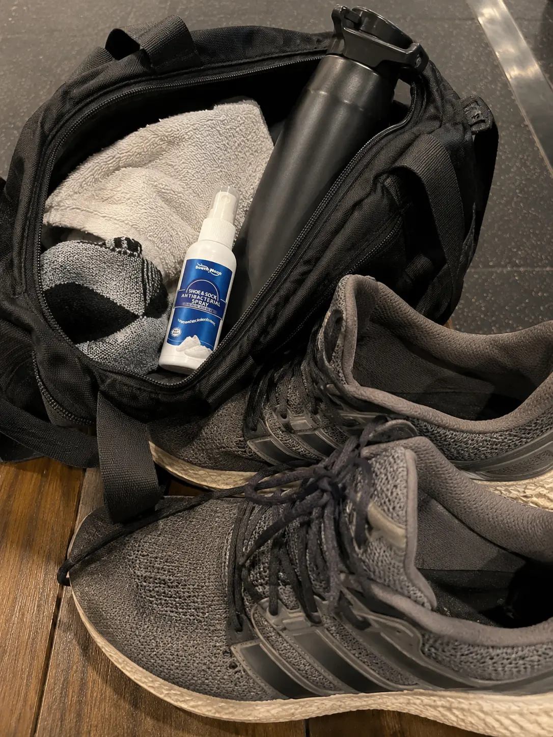 Shoe Reset bottle next to trainers in a gym bag