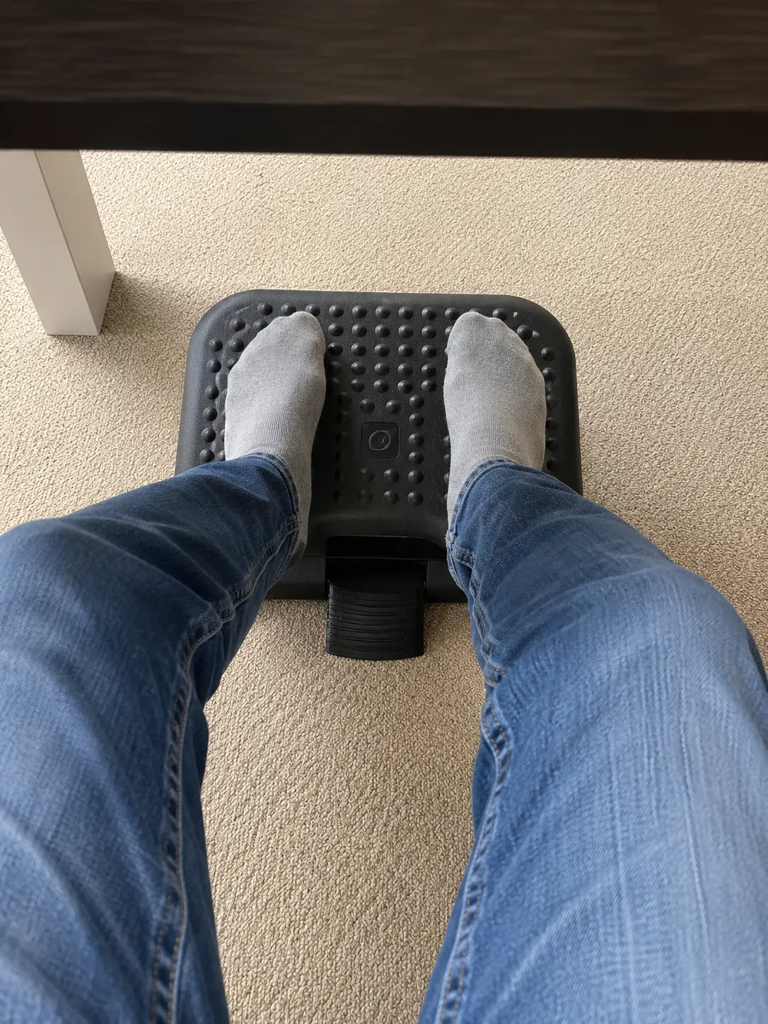 Feet resting on the Ergonomic Footrest under a desk