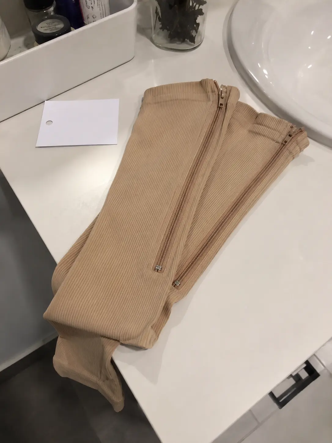 Folded beige Easy Zip Compression Socks on a bathroom counter