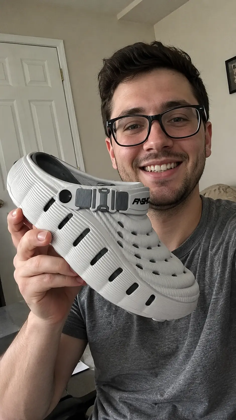 Customer holding his gray Cloud Recovery Slippers at home